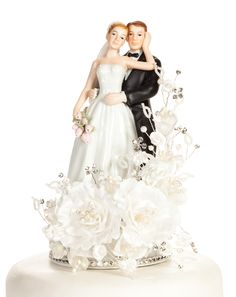 a bride and groom figurine on top of a wedding cake with white flowers