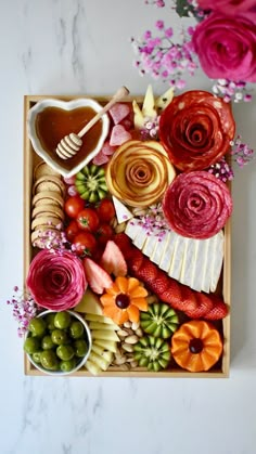 an assortment of fruits and flowers in a wooden tray