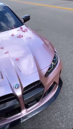 a pink sports car parked on the side of the road with flowers all over it