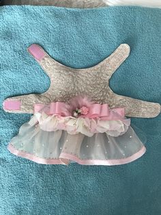 a baby's pink and white dress hanging on a blue towel