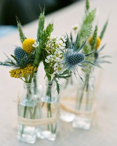 three glass vases with flowers in them sitting on a table