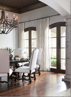 a dining room table with white chairs and a chandelier hanging from the ceiling