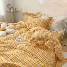 an unmade bed with yellow and white checkered sheets, pillows and stuffed animals