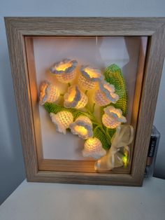 a shadow box with flowers in it and a light up frame on the table next to it