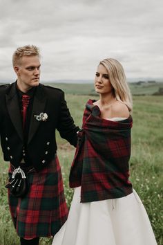 a man and woman dressed in kilts standing next to each other on a field