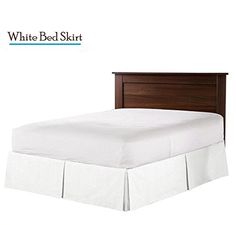 a bed with white bedskirt and wooden headboard