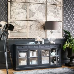 a living room with an old world map on the wall and a tripod light