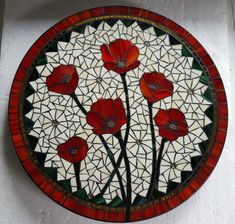 a red and white plate with flowers painted on the front, sitting on a wall