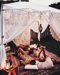 a woman laying on top of a bed under a canopy