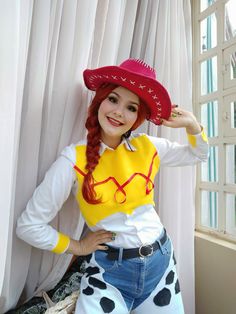 a woman with red hair wearing a yellow and white shirt, cowboy hat and jeans