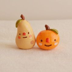 two small figurines sitting next to each other on a white tablecloth covered surface