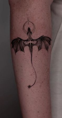 a black and white photo of a dragon tattoo on the right arm with an arrow