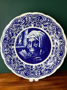 a blue and white plate sitting on top of a wooden table next to a green wall