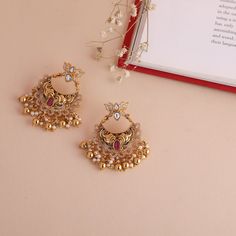 Description : These lotus chandbali earrings with antique gold polish are crafted to attract attention. It has a beautiful design with kempu and CZ stones paired with drop pearl beads in a depicting nakshi arrangement. Details & Specifications: Materials used: Brass Alloy with Antique Plating Weight - 21.45 gm Length - 5 cm Make it custom : Want to make it a custom Earrings ? Sure! Reach out to us at support@tarinika.com and we’ll be happy to make possible modifications at no extra cost. Feel fr Cheap Gold Bollywood Chandbalis, Luxury 22k Gold Traditional Chandbalis, Elegant Chandbalis With Intricate Design For Puja, Elegant Chandbalis For Puja With Intricate Design, Gold Dual-tone Chandbalis For Celebration, Gold Chandbali Chandelier Earrings In Temple Style, Gold Chandbali Temple Chandelier Earrings, Gold Chandbali Jhumkas With Peacock Design, Gold Chandbali Temple Jewelry Chandelier Earrings