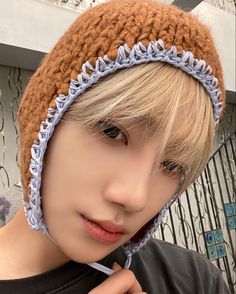 a boy with blonde hair wearing a crocheted hat and looking at the camera