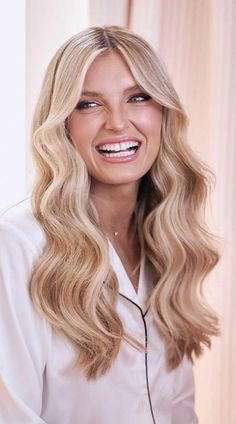 a woman with long blonde hair smiling at the camera