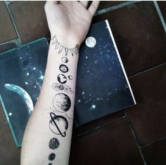 a person with a tattoo on their arm that has planets and sun in the background