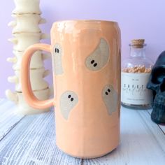 a ceramic mug with two faces on it sitting next to a skull and some bottles