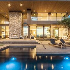 a modern house with an outdoor pool and lounge chairs in the front yard at night