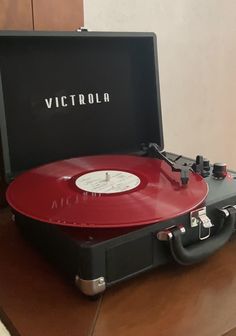 an old record player sitting on top of a wooden table next to a case with the word victoria printed on it