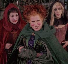 three women dressed up as witches and one is smiling at the camera with her hands on her hips