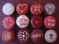 red cupcakes decorated with white frosting and designs on them are arranged in the shape of hearts