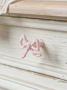 a pink bow tie on the handle of a white dresser