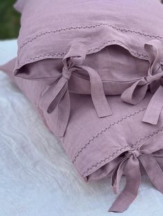 a pink pillow with bows on it sitting on a white sheet