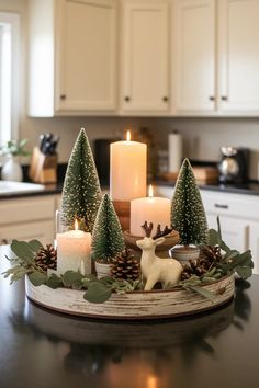 candles are sitting on a tray with evergreen trees and deer figurines in the center