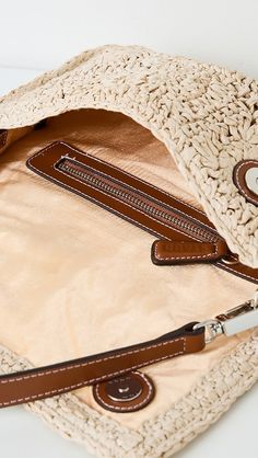 an open purse sitting on top of a white table next to a brown leather handle