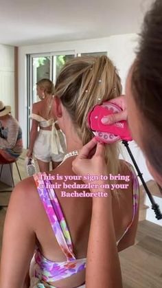 a woman is combing her hair in front of a mirror while another woman watches