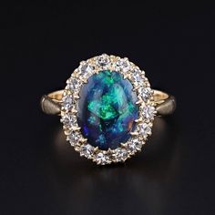 Vintage Black Opal Ring: This Art Deco ring (circa 1920-1930) features a stunning black opal set in a halo of single cut diamonds set in 18k gold. The black opal weighs approximately 2.05ct and the combined weight of the diamonds weighs 0.75ct. The face of the ring measures 0.6 inches from top to bottom by 0.5 inches wide, and it is in great condition.  The ring is a size 6.25, but it can be resized free of charge. The ring weighs 3.82 grams.  Upon purchase, your ring will arrive elegantly packa Luxury Black Opal Ring Elegant Style, Art Deco Opal Ring, Black Oval Opal Ring For Formal Occasions, Formal Opal Ring With Halo Setting, Formal Opal Diamond Ring With Halo Design, Formal Fine Jewelry Opal Ring With Halo Design, Classic Opal Ring With Halo Setting For Formal Occasions, Formal Yellow Gold Opal Ring With Halo Design, Elegant Formal Opal Ring With Halo Design