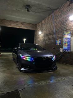 a car parked in a parking garage with its lights on and the hood up open