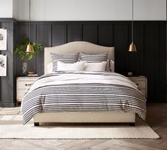 a bed with black and white striped comforter on top of it in a bedroom