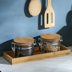 two wooden spoons are on the counter next to some jars with food in them