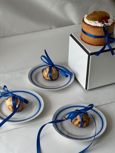 three plates with pastries tied in blue ribbons on a white tablecloth covered table