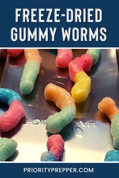 a close up of candy worms on top of a cookie sheet with the words freeze - dried gummy worms