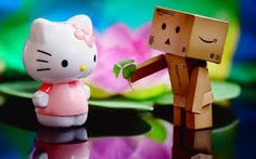 a hello kitty figurine is standing next to a cardboard man with a flower in his hand