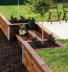 a wooden garden bench sitting on top of a lush green field next to a tree