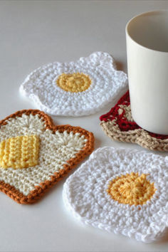 three crocheted coasters and a coffee cup on a white table with a mug in the middle