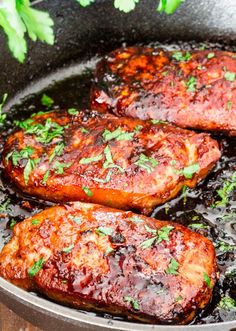 pork chops cooking in a skillet with sauce and parsley on the side