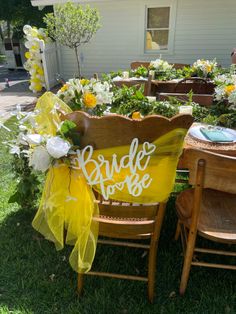 a couple of wooden chairs sitting on top of a lush green field covered in flowers