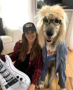 a woman sitting on the floor next to a dog with glasses and a guitar in front of her