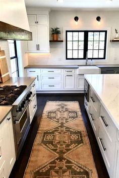 a kitchen with white cabinets and an area rug on the floor in front of the stove