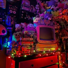 an old tv sitting on top of a dresser in front of a pile of stuffed animals