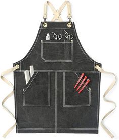 a black apron with scissors and other items on the front, hanging from two white straps