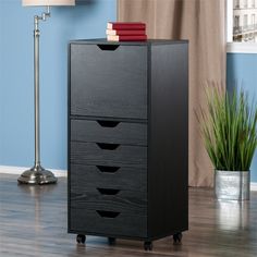 a black filing cabinet sitting on top of a hard wood floor next to a lamp