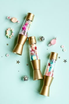 three gold tubes filled with candy sitting on top of a blue surface