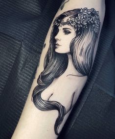 a woman with long hair and flowers on her head is shown in this black and white tattoo