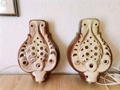 two brown ceramic vases sitting on top of a wooden table next to a wall